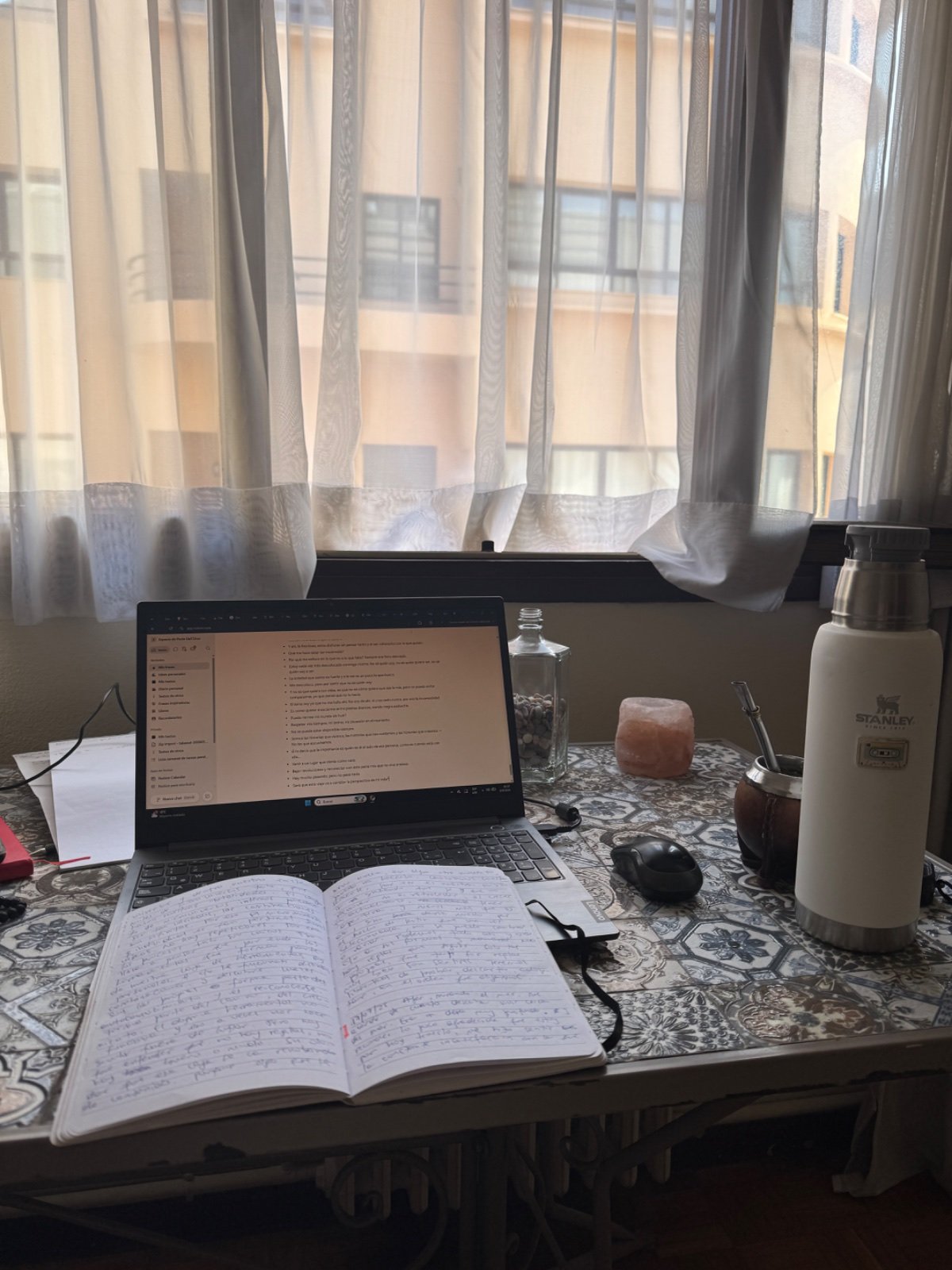 Cuaderno escrito a mano, abierto sobre el escritorio junto al mate